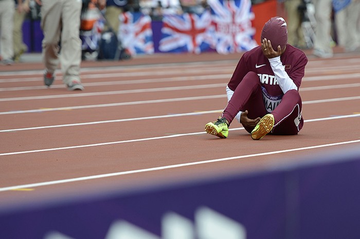Noor Hussain Al-Malki của Qatar ngồi khóc sau khi bị chấn thương ở vòng loại 100m nữ.